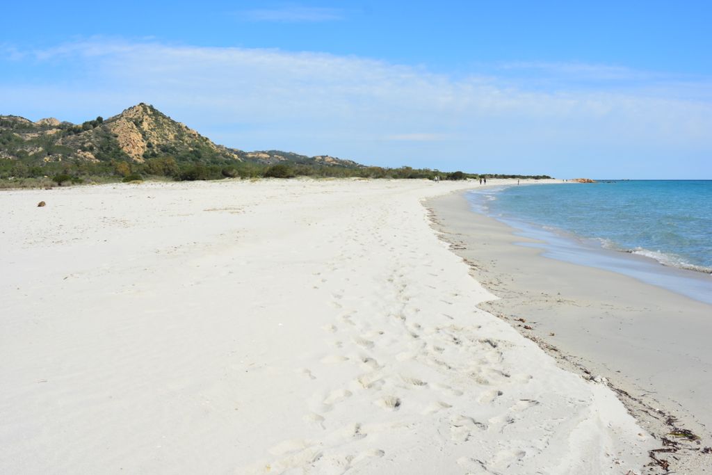 Tranquil white sand beach with turquoise waters and mountainous backdrop in Siniscola, Sardinia.